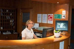 a woman sitting at a counter in at Family Apartments by ASTORIA Hotel & Medical Spa in Karlovy Vary