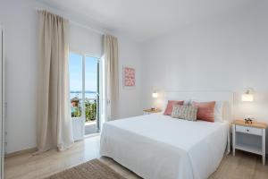 a white bedroom with a white bed and a window at Reana Elegant Apartments in Barbati