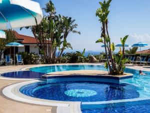 a swimming pool at a resort with palm trees at Nice residence in San Nicol di Ricadi with pool in Ricadi