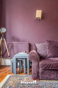 Stunning 3 Bdr Apartment 5 Min From Haymarket في إدنبرة: غرفة معيشة أرجوانية مع أريكة وطاولة