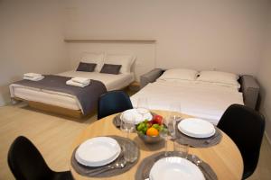 a room with two beds and a table with a bowl of fruit at Dea Del Mar Apartments in Izola