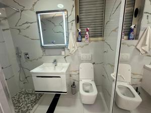 W łazience znajduje się umywalka, toaleta i lustro. w obiekcie ESTO's Apartament near Tirana Airport 1 - Self CheckIN -Netflix - FREE Parking w mieście Valjiosi