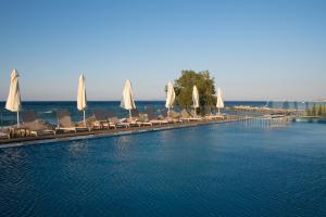 uma piscina com cadeiras e guarda-sóis brancos em Golden Coast Boutique - Luxury Living em Kypseli