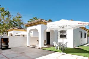 ein weißes Haus mit einem Tisch und einem Regenschirm in der Unterkunft Casa Paqui 3 in Roche