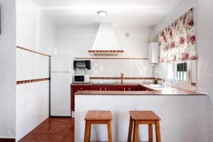 eine Küche mit einer Spüle und 2 Holzhockern in der Unterkunft Casa Paqui 3 in Roche