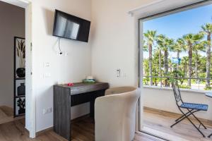 Zimmer mit einem Schreibtisch und einem Fenster mit Palmen in der Unterkunft Affittacamere Mare nel Cuore in Torre Grande