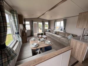 ein Wohnzimmer mit einem Sofa und einem Tisch in einem Wohnwagen in der Unterkunft Lolas Lodge in Lossiemouth