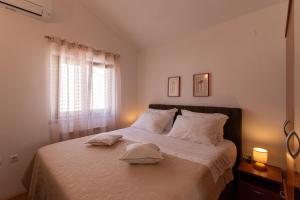 a bedroom with a bed with white sheets and a window at Apartments Villa Nataly in Zadar