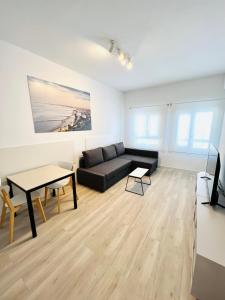 a living room with a black couch and a table at Apartamentos Hotel Puente de Hierro in Benicàssim