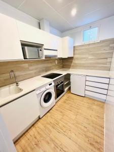 uma cozinha com armários brancos, um lavatório e uma máquina de lavar louça em Apartamentos Hotel Puente de Hierro em Benicàssim