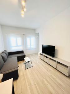 a living room with a couch and a flat screen tv at Apartamentos Hotel Puente de Hierro in Benicàssim