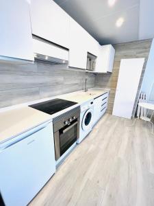 cocina con armarios blancos, lavadora y secadora en Apartamentos Hotel Puente de Hierro, en Benicàssim
