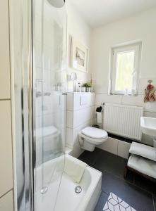 a white bathroom with a shower and a toilet at Ferienwohnung am Olantis in Oldenburg +16 photos