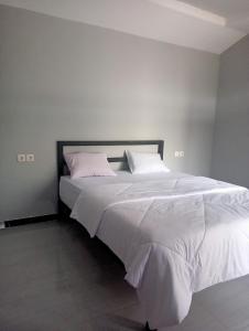 een slaapkamer met een groot bed met witte lakens en kussens bij Mount Rinjani Guest House in Sajang
