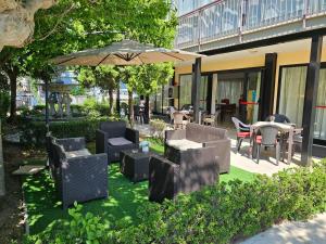 patio z krzesłami, stołami i parasolem w obiekcie Hotel Paradiso w Rimini