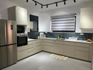 a kitchen with white cabinets and a sink and a refrigerator at Aramis Suite in Neot Golan