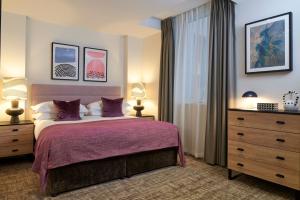 um quarto com uma cama com lençóis roxos e uma janela em Cheval Harrington Court at South Kensington em Londres