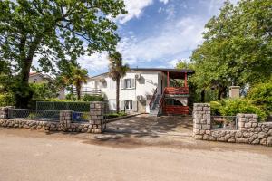 a house with a stone fence in front of it at Apartments Danica by EL-PI TOURS in Njivice