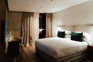 um quarto de hotel com uma cama grande com almofadas verdes em Del Bono Central Hotel em San Juan