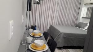 Una habitación con una mesa con dos tazas y una cama en Flats Asa Norte CLN 110 by CentoEdez en Brasilia