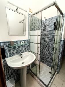 uma casa de banho com um lavatório e uma cabina de duche em vidro. em La Residenza B&B em Giba