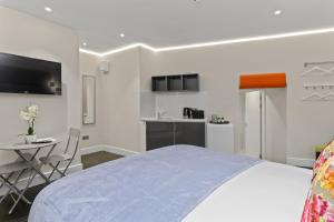 a bedroom with a bed and a table and a kitchen at Modern Studio Flat in London