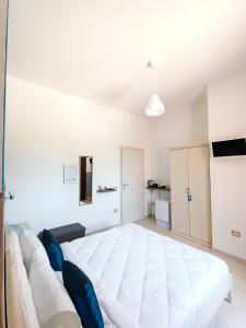 a white bedroom with a large white bed and blue pillows at La Residenza B&B in Giba