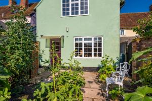 a green house with two white chairs in the garden at Pats' Place Long Melford in Sudbury