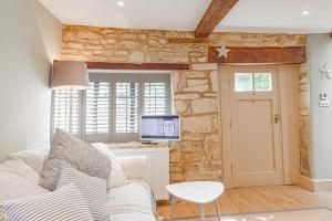 a living room with a white couch and a tv at Mill House Cottage - Star Stay on The Cotswold Way in Harescombe