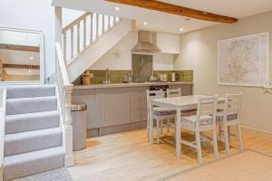 a kitchen with a table and chairs and a staircase at Mill House Cottage - Star Stay on The Cotswold Way in Harescombe