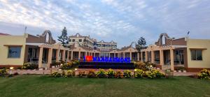 a large building with a flower garden in front of it at Aqua Marina Drive Inn in Mandarmoni