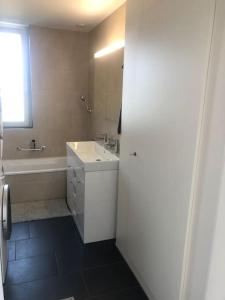 ein Badezimmer mit einem Waschbecken, einer Badewanne, einem Waschbecken und einem Spiegel in der Unterkunft Atikka, Ático, penthouse in Luzern