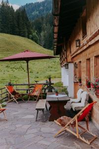eine Terrasse mit Stühlen, einem Tisch und einem Sonnenschirm in der Unterkunft Hasenalm in Schliersee