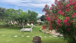 einen Garten mit zwei weißen Stühlen und rosa Blumen in der Unterkunft Bed&Breakfast Vanni in Privlaka