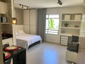 a bedroom with a bed and a desk and a kitchen at Flats Condomínio Park Ville by CentoEdez in Brasília