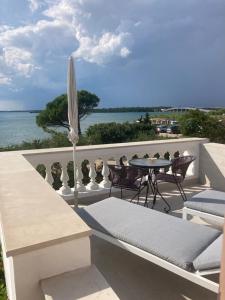 eine Terrasse mit einem Sonnenschirm, einem Tisch und Stühlen in der Unterkunft Bed&Breakfast Vanni in Privlaka