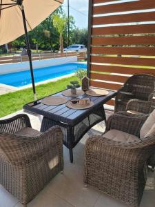 a table with chairs and an umbrella next to a pool at Sol Greco Apartment in Skala Rachoniou