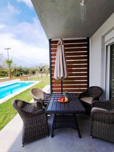 a patio with a table and chairs and a pool at Sol Greco Apartment in Skala Rachoniou