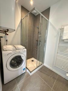 uma máquina de lavar roupa na casa de banho com um chuveiro em Tiny House moderne et son jardin privé - 5mn Roanne 