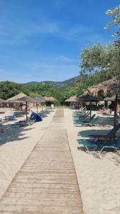 a sandy beach with chairs and umbrellas and a pathway at Sol Greco Apartment in Skala Rachoniou