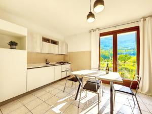 een keuken met een tafel en stoelen en een raam bij Appartamento nella natura [borghi più belli d'italia] in Tovena