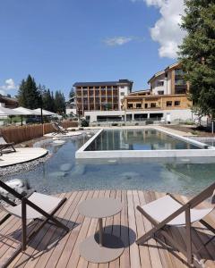 a swimming pool with two chairs and a table at Valbella Resort in Lenzerheide