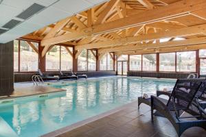 a large swimming pool with chairs and a wooden ceiling at Dormio Resort Les Portes du Mont Blanc in Vallorcine