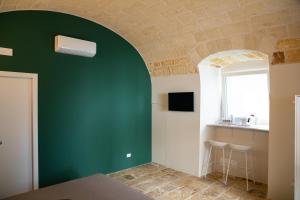 - une chambre avec un mur vert, une table et une fenêtre dans l'établissement Aqua - Letto e Colazione, à Acquaviva delle Fonti