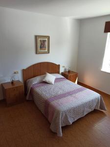 a bedroom with a bed with a purple comforter and a window at Casa en Puerto de Bares in Bares