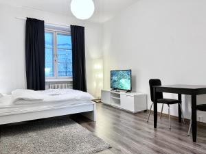 um quarto com uma cama, uma secretária e uma televisão em Beautiful Central Apartment Helsinki em Helsínquia