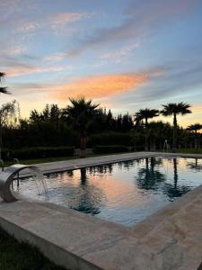 una piscina con fontana di fronte al tramonto di Les portes de l'atlas a Fes