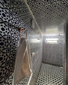 y baño con ducha y azulejos blancos y negros. en Les portes de l'atlas en Fez