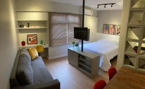 a bedroom with a bed and a couch and a tv at Flat Condomínio Garden Park by CentoEdez in Brasília