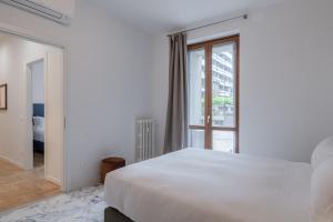 Un dormitorio con una gran cama blanca y una ventana en RELSTAY - CityLife - 2BR en Milán